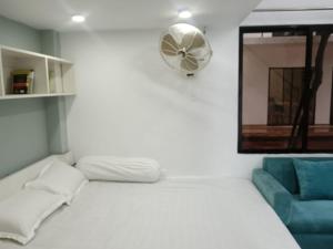 a white bed with a fan and a blue couch at Nodir Neer - Nest by the River in Fatepur