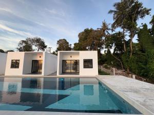 a white house with a swimming pool in front of it at Pine Bungalow Krabi in Klong Muang Beach