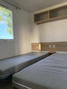 two beds in a room with a window at L'Eleganzia Piscines et nature en Normandie in Litteau