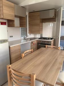 a kitchen with a wooden table and a refrigerator at L'Eleganzia Piscines et nature en Normandie in Litteau