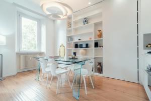 una sala da pranzo con un tavolo di vetro e sedie bianche di On the Tiber- Luxury house a Roma
