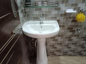 a white sink in a bathroom with a tiled wall at Nodir Neer - Nest by the River in Fatepur +21 photos