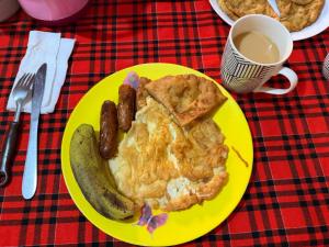 a yellow plate of food with sausage and a pie at Greenfield Homestay -Full board in Oloitokitok 