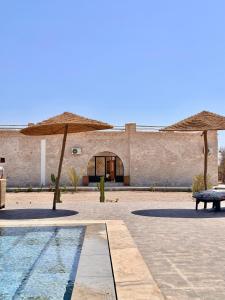 a building with two umbrellas and a swimming pool at Riad Maj Nia House in Essaouira