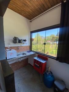 a kitchen with a red stove and a large window at Chalés Lavras de Minas - Belém in Lavras Novas