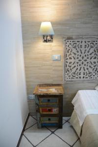 a bedroom with a bed and a table with a lamp at Syrakosia a Ortigia in Syracuse