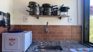 a kitchen with a sink and a microwave at Chalés Lavras de Minas - Belém in Lavras Novas +15 photos