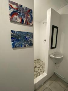 a bathroom with a toilet and two paintings on the wall at 1 Cora Terrace Accommodation in Gqeberha