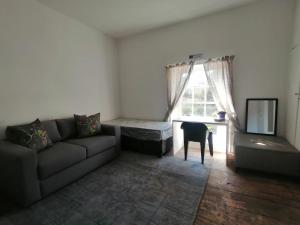 a living room with a couch and a bed and a window at 1 Cora Terrace Accommodation in Gqeberha