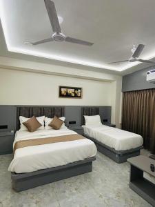 a bedroom with two beds and a ceiling fan at Hotel sun town in Ahmedabad