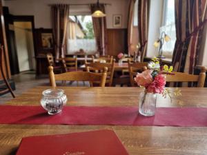 a table with a red napkin and a vase of flowers at Deutsches Haus in Buchholz in der Nordheide