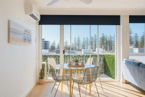 una sala da pranzo con tavolo e sedie e una grande finestra di 2 BR Burleigh Beach Family Apartment a Gold Coast