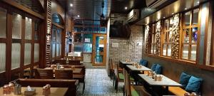 a restaurant with wooden tables and chairs and a tv at SriKrishna Paradise Hotel Thane Navi Mumbai in Thane +54 photos