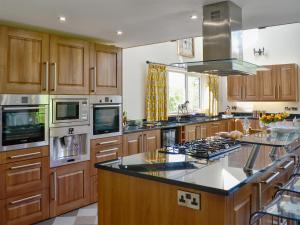 a large kitchen with wooden cabinets and a large island at Holmegarth in Plumbland