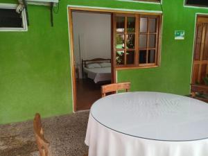 a green room with a table and a bed at Hotel Santa Helena in Leticia
