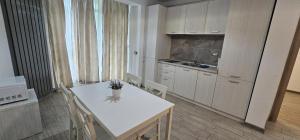 a kitchen with a white table and chairs in a room at Azizi Apartment Beach Pool & Spa Resort in Mamaia Nord