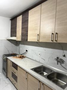 a kitchen with a sink and wooden cabinets at Apartman TADEJ in Zvornik +5 photos