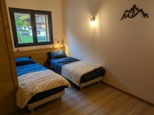 twee bedden in een kamer met een raam bij Chalet La Tanière avec Sauna in Le Grand-Bornand