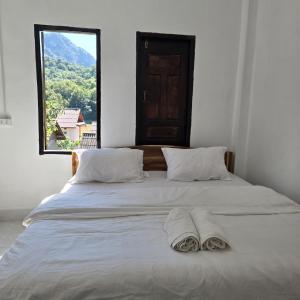 a bed with two towels on it with a window at Pinkeo Guesthouse in Nongkhiaw