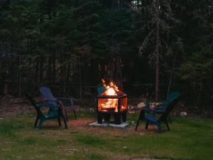drie stoelen rond een vuurplaats in een tuin bij Oslo Scandinavian Getaway Spa & Pet-Friendly in Saint Come