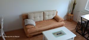 a brown couch in a living room with a table at Wohnung Mia in Sangerhausen +9 photos