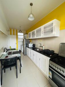 a kitchen with white cabinets and a table in it at Two-bedroom apartment - Spacious, with a gym and well-equipped in Beira