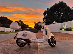 a white scooter parked on the side of a road at Adrift Guesthouse in St Francis Bay +3 photos