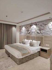 a bedroom with a large bed and a wall with flowers at Burj Al Hayat Furnished Apartment - Jazan in Jazan