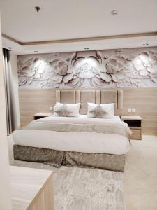 a bedroom with a large bed with flowers on the wall at Burj Al Hayat Furnished Apartment - Jazan in Jazan