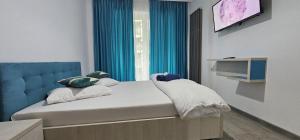 a bedroom with a bed with a blue headboard and a television at Beach Pool & Spa Resort Mamaia Nord Alezzi piscina incalzita in Mamaia Nord