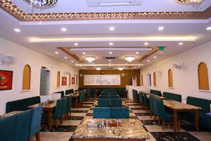 una sala de banquetes con mesas y sillas y una pantalla de proyección en Hotel Shree Khodiyar By Rangoli Udaipur, en Udaipur