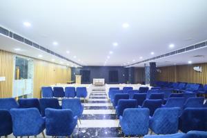Una sala de conferencias con sillas azules y un escenario. en Hotel Shree Khodiyar By Rangoli Udaipur, en Udaipur