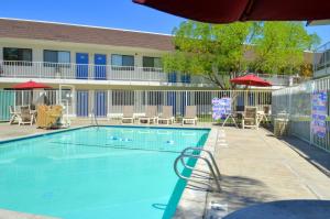 a swimming pool with chairs and umbrellas next to a building at Motel 6-Santa Nella, CA - Los Banos - Interstate 5 in Santa Nella