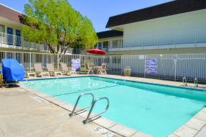 una gran piscina con sillas y un edificio en Motel 6-Santa Nella, CA - Los Banos - Interstate 5, en Santa Nella