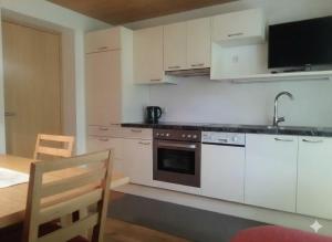 a kitchen with white cabinets and a sink and a table at Ferienwohnungen Abel in Damuls