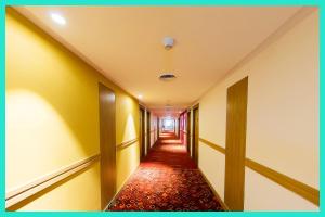 a corridor with yellow walls and a red carpet at HOTEL CD!M PALACE - Comfortable & Serene Stay Near Spiritual Destinations - Free Wi-Fi and Parking Facilities # Fully Air Conditioned Hotel - Near Kashi Vishwanath Temple !! in Rāmnagar