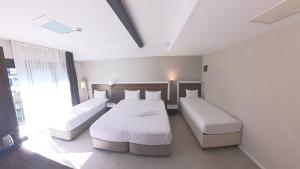 a hotel room with two beds and a window at Lulubay Rooms & Suites in Kuşadası
