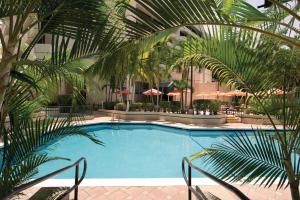 a swimming pool with palm trees in a hotel at Modern Two-Room Suite with Gym and Pool in Yamato