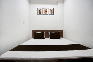 ein Schlafzimmer mit einem weißen Bett und schwarzen Kissen in der Unterkunft HOTEL O MAJESTIC INN in Jabalpur