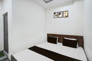 ein Schlafzimmer mit einem weißen Bett und schwarzen Kissen in der Unterkunft HOTEL O MAJESTIC INN in Jabalpur