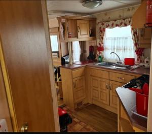 a small kitchen with wooden cabinets and a sink at The Chase & Grange caravan park ingoldmells ref F in Addlethorpe