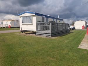 a small house with a deck in a yard at The Chase & Grange caravan park ingoldmells ref F in Addlethorpe