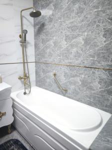 a bathroom with a white bath tub next to a toilet at Апартаменты рядом с ТРЦ Mega и парком Первого Президента in Almaty