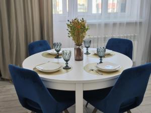 a table with blue chairs and a white table with plates and glasses at Апартаменты рядом с ТРЦ Mega и парком Первого Президента in Almaty