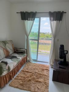 een woonkamer met een bank en een groot raam bij Apartamento dois quartos com uma suíte in Ananindeua
