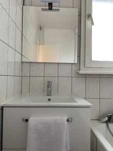 a white bathroom with a sink and a mirror at Maison Tivoli in Huningue