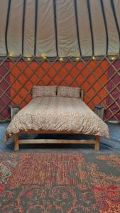 un letto in una yurta con una parete rossa di Hillside Retreats a Machynlleth