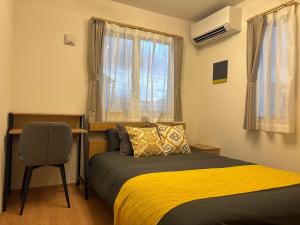 Un dormitorio con una cama y un escritorio y una ventana. en Hotel Tomas Shirahama, en Uruma