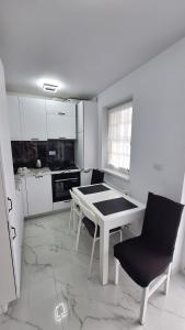 a white kitchen with a table and two chairs at Apartament Ovidiu in Horpaz