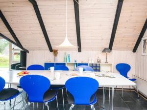 a dining room with a white table and blue chairs at 4 star holiday home in Rømø in Kongsmark +30 photos